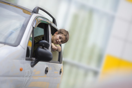 The boy looks out of the car window to hurry his parents and continue the trip