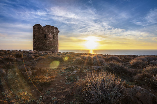 Cala Domestica Beach, spanish tower at sunset in long exposure and flare effect, Buggerru, Sardinia
