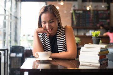 Asian woman relaxing and reading a book in the cafe. Women lifestyle concept.