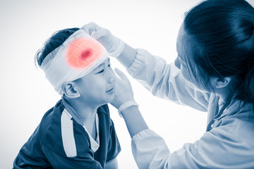 Sports injury. Doctor makes a bandage on head patient, on white.