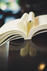 Curled paper heart shape with blurred bokeh of cafe.