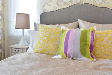 female's bedroom with colorful pillows on bed in vintage style bedroom.