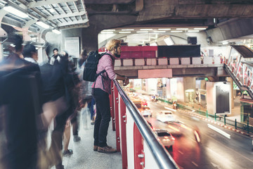 Fototapeta premium Hipster bearded man standing in the train station with people motion background while traveling at night.
