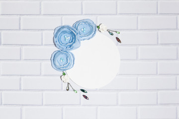 White Background With Handmade Garland With Gentle Blue Ranunculus Flowers,Roses and Crystals, Lying Flat on the White Brick Wall, Top View. Have a Empty Circle Place For Your Text.