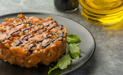 Delicious the tartare sauce from a salmon rich in omega 3 oil with aromatic herbs and spices with a lemon on black background. Healthy and diet food.