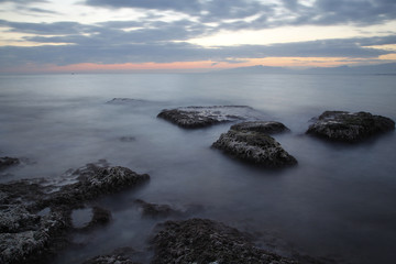 Sea coast in a long exposure shot at sunset, with blurred water