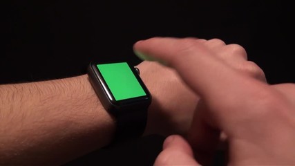Hand gesturing in a smartwatch with green screen, chroma, black background. Man with smartwatch placed on the left wrist, right hand interacts with the screen on and off. Adrian