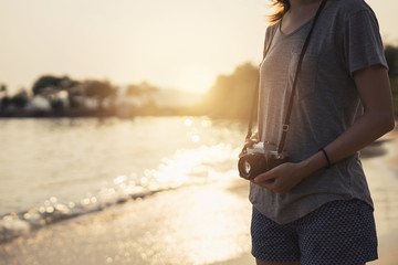 Young woman traveller with retro camera on the beach