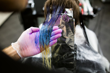 Man in gloves is dying long blue hair colorfull. Beauty salon, Barber.
