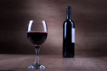 Glass of wine with a bottle on a wooden backgound