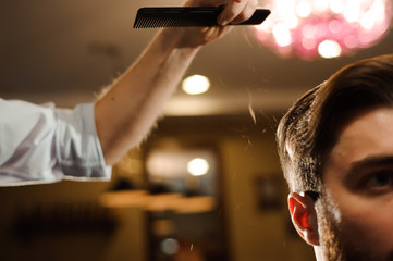 Master cuts hair and beard of men in the barbershop