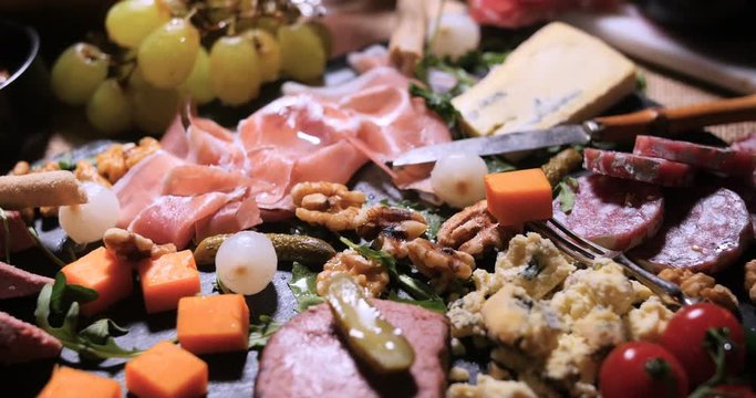 Dolly close up push in view of a platter of cured meat (charcuterie), ham, salami, pate and cheese