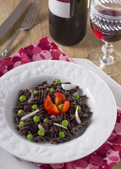 squid ink pasta with tomato, peas and wine in the white dish
