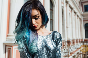 Fashion portrait of gorgeous girl with blue dyed hair long. The beautiful evening cocktail dress.