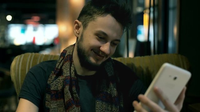 Young man browsing internet on tablet and laughing at something
