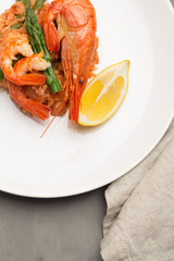 rice with shrimp and asparagus with lemon on a plate, napkin close-up view from above.