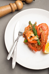 rice with shrimp and asparagus in a tomato sauce on a white plate.