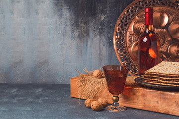 Passover holiday concept with wine, matzoh and seder plate over dark background