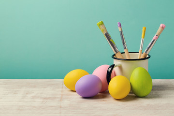 Easter holiday background with handmade painted eggs and brushes on wooden table