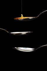 Honey pouring from spoon against a dark background