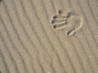 Fototapeta na wymiar Sand waves on the beach and handprints