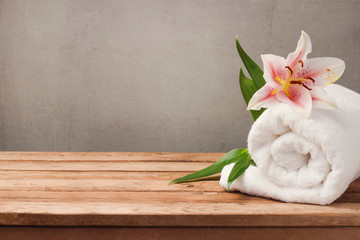 Spa and wellness concept with white towel and flower on wooden table over rustic background