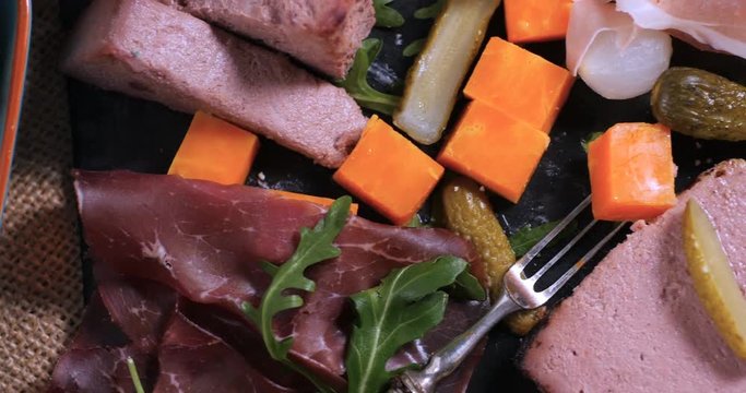 Dolly extreme close up  view of a platter of cured meat (charcuterie), ham, salami, pate and cheese