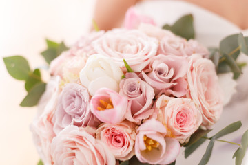 Brides bouquet of roses, tulips and eucalyptus, in her hands