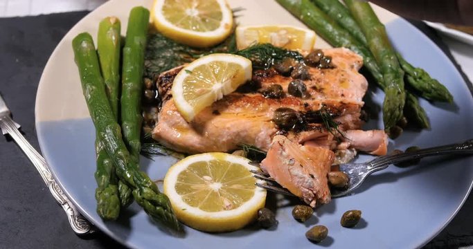 Sprinkling salt over a delicious roasted organic salmon with capers and dill