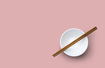 Top view of chopsticks with bowl on pink background.