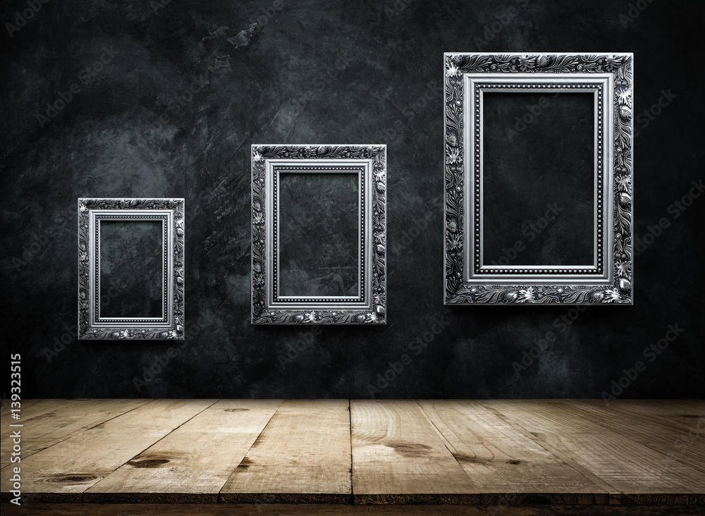 Wall mural silver antique picture frame on dark grunge wall with wooden table top, empty ready for product disp