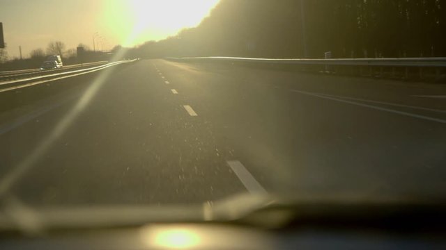 Driving into a sunset on highway with flare