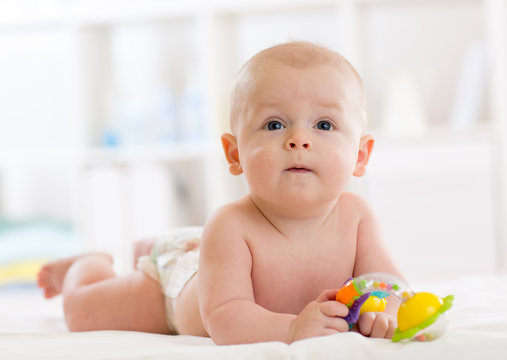 Cute baby boy weared diaper lying on bed at nursery