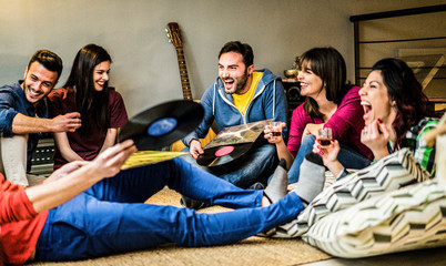 Happy friends having party listening vintage vinyl disc albums at home