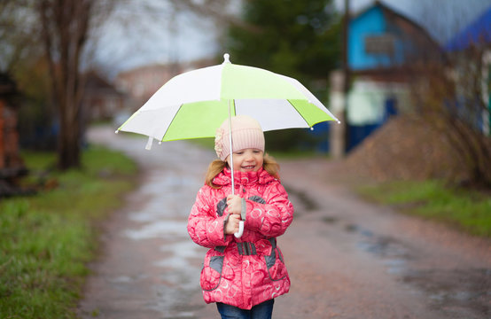 Little smiling happy girl with green umbrella in spring