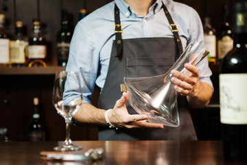 Wineglass at barcounter at background of sommelier with emty decanter