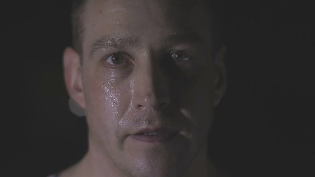 Intense sweaty face of young muscular man pulling rope