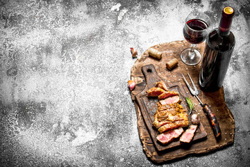 Meat grill. Sliced pork with red wine on a wooden tray. on rustic background.