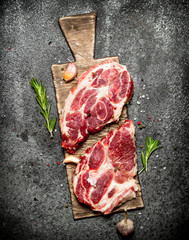 Raw meat background. A piece of Raw pork chops with fragrant spices and fresh herbs. On rustic background.