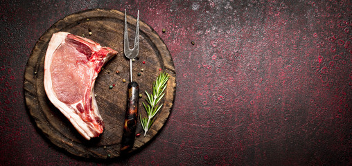 Raw meat background. Raw piece of pork with a sprig of rosemary. On rustic metal background.