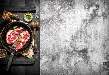 Raw meat background. Raw pork chop in an old pan with spices and herbs.