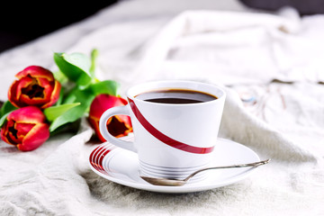 Cup of fresh coffee onl linen napkins Tulips next to cup