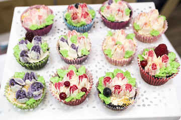 Delicious cupcakes with buttercream and fruits