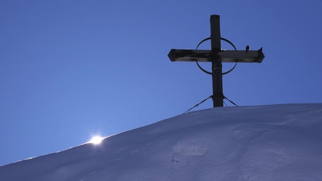 Wooden cross on top of snow covered hill, time lapse footage of setting sun