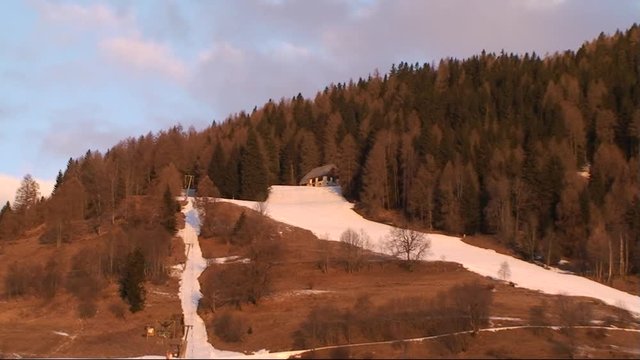 Die Skipiste in Krakauebene im warmen roten Licht der aufgehenden Wintersonne (Kamerazoomfahrt, Totale)