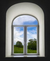 white semicircular modernist windows on a black wall.summer, sky, clouds, trees, grass, meadow in the window