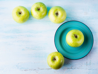Green pastel background with apples flowers. Healthy food concept backdrop for writing text. Top view