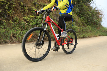 young woman riding mountain bike on forest trail