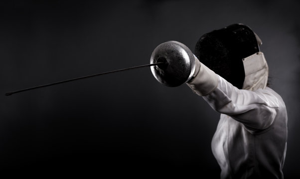 Portrait of woman wearing white fencing costume practicing with the sword.