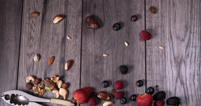 Stop motion view of berries amd dry fruits sliding on a wooden table